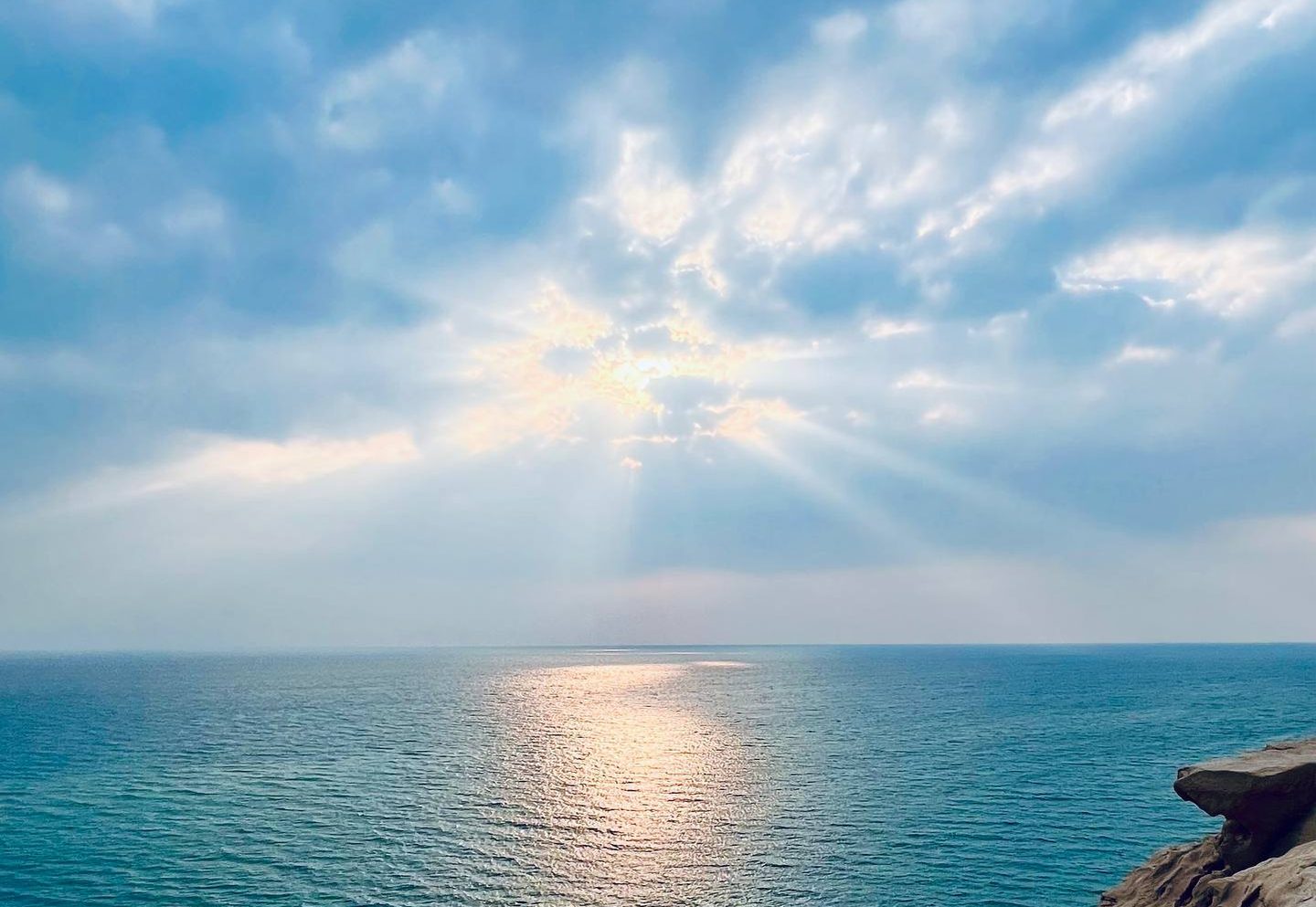Sunbeams breaking through cloud over the Persian Gulf, seen from the rocky Kish coast